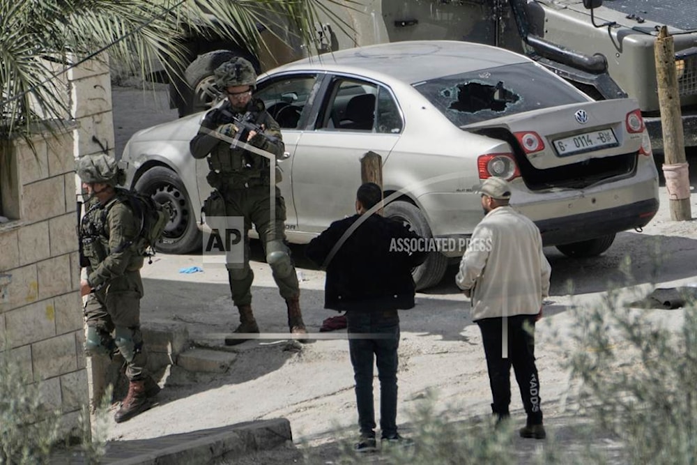 An Israeli soldier aims his weapon at a Palestinian man during an army operation in the Al-Ain refugee camp near the West Bank city of Nablus, Wednesday, March 19, 2025 (AP)